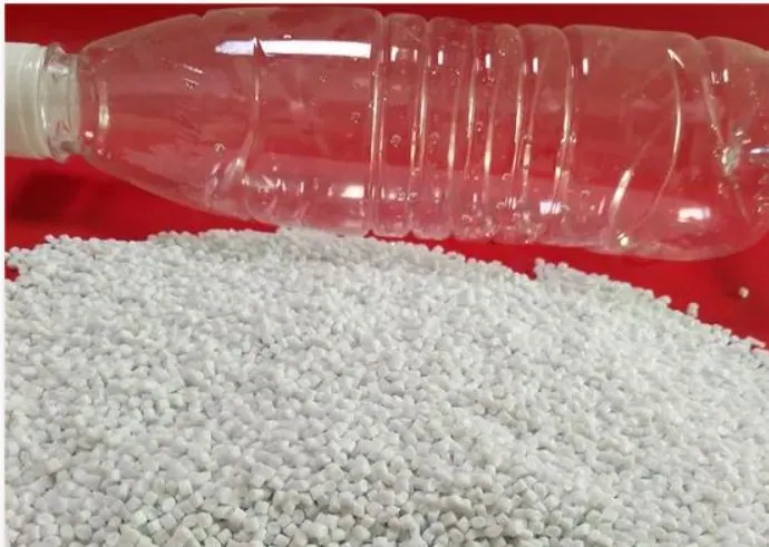 PET resin chips in front of a clear plastic bottle