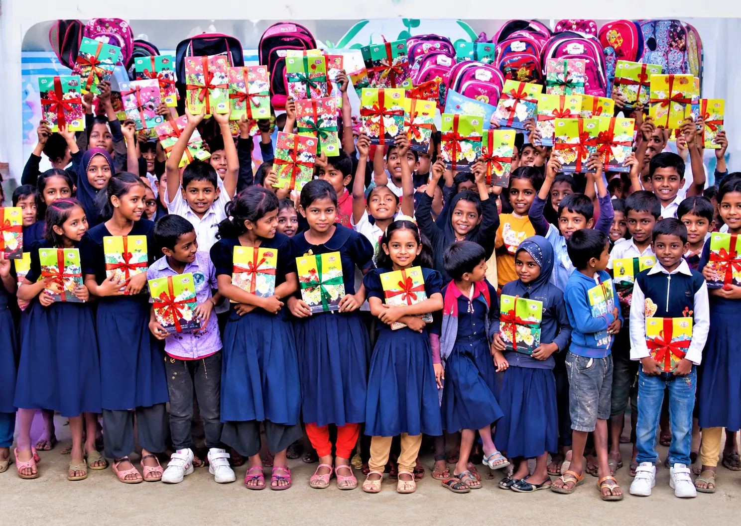 Schoolchildren in blue uniforms smiling and holding up gift-wrapped school supplies